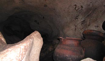 Pots line the walls and sit in pockets in the cave