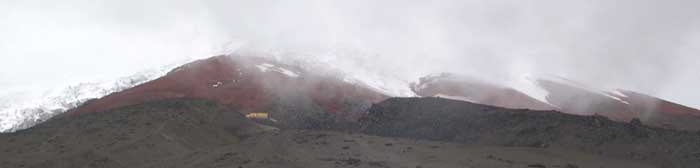 top of the volcano with yellow visitor's center and white glaciers