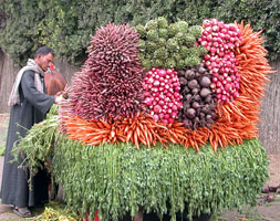 A man with a cart with stacked vegetables about 4 feet high