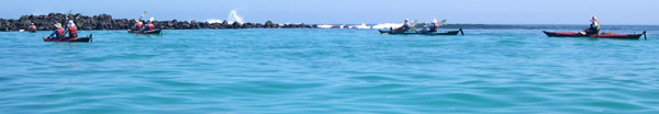 Kayakers against black rock beach